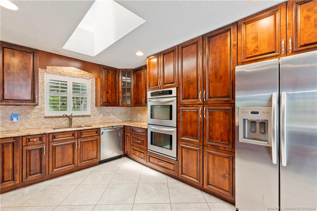 18770 Southeast River Ridge Road Jupiter, FL 33469 - Photo 7 of 81 a kitchen with stainless steel appliances granite countertop a refrigerator and a sink