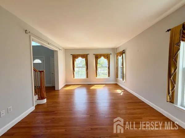 a view of an empty room with window and wooden floor