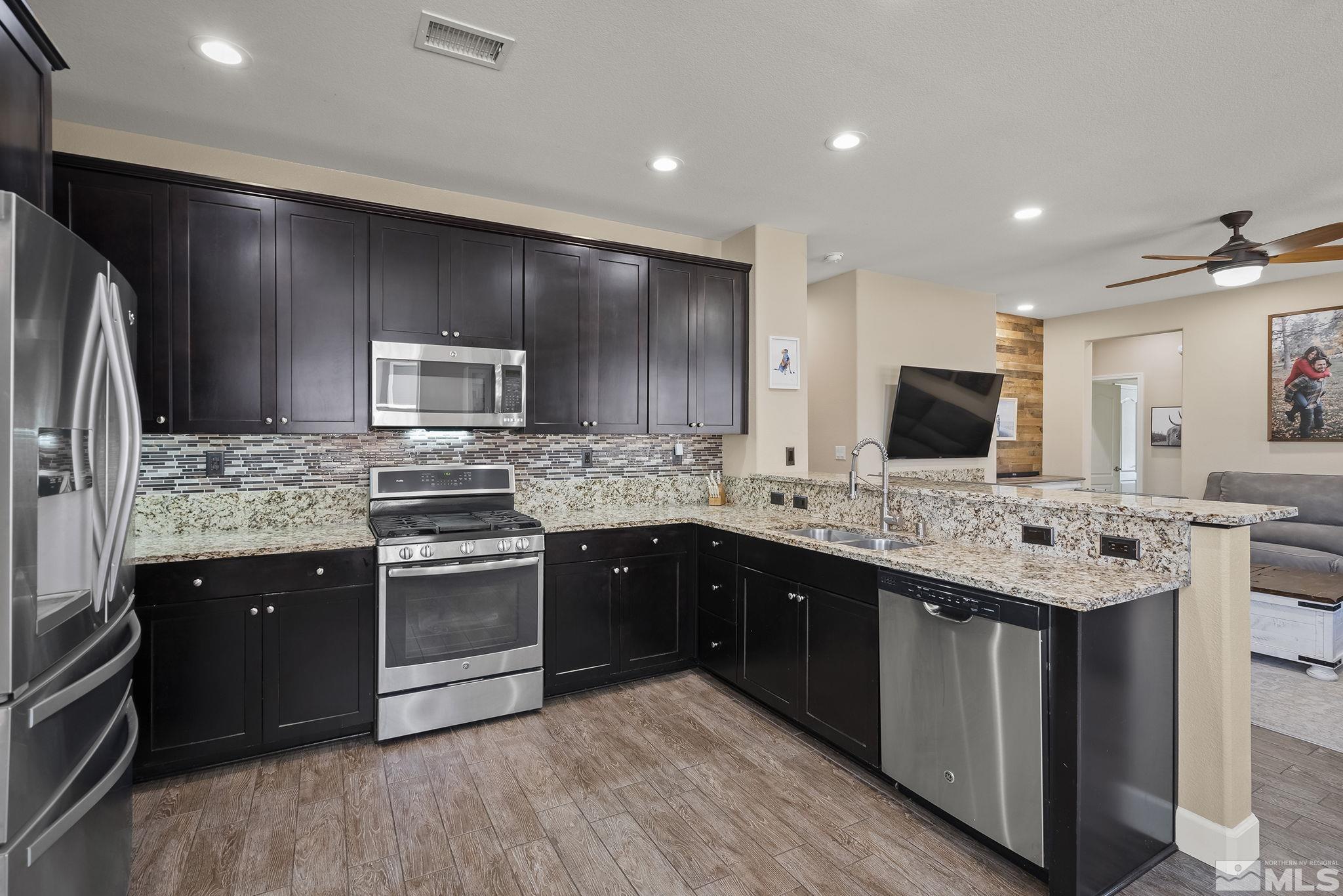 2135 Blue Oaks Drive Reno, NV 89521 - Photo 10 of 23 a kitchen with stainless steel appliances kitchen island granite countertop a sink stove and refrigerator