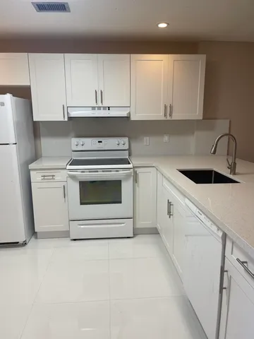 a kitchen with white cabinets and white appliances
