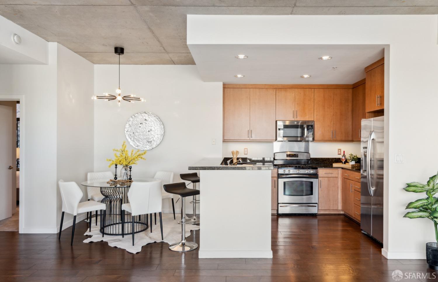 288 3rd Street, Unit 201 Oakland, CA 94607 - Photo 7 of 51 a kitchen with stainless steel appliances granite countertop a stove top oven a refrigerator a sink and a dining table with wooden floor