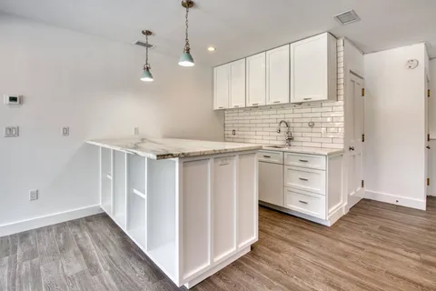 a kitchen with stainless steel appliances white cabinets and wooden floors