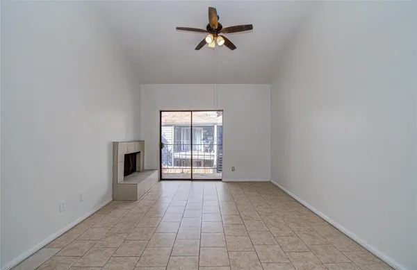 a view of n empty room with a ceiling fan and window