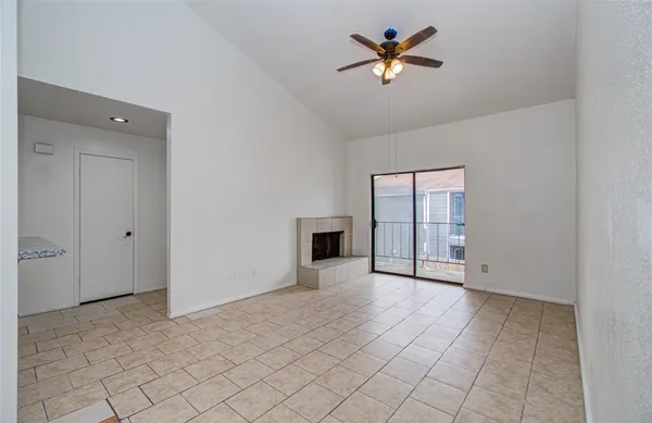 an empty room with chandelier fan and windows