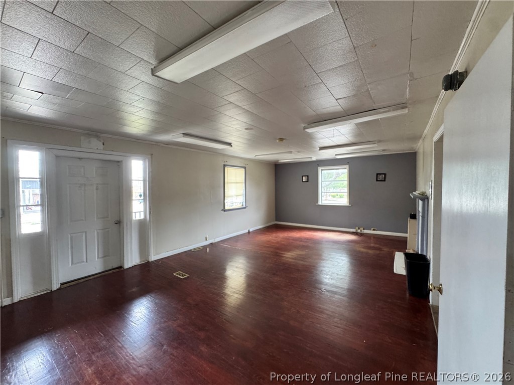 202 Main Street Hamlet, NC 28345 - Photo 3 of 7 an empty room with wooden floor and windows