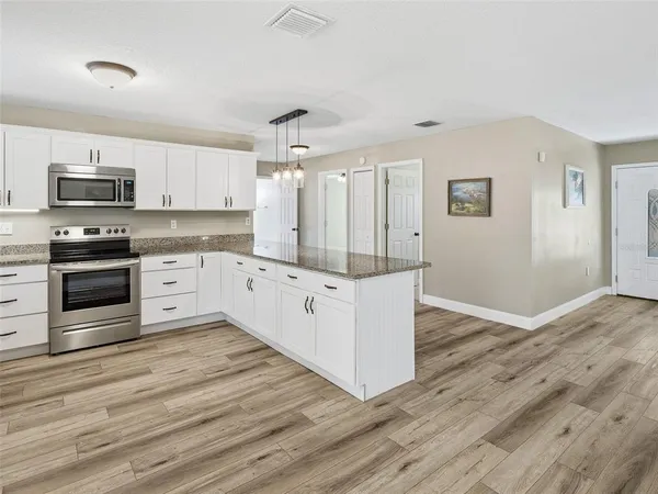 a kitchen with stainless steel appliances kitchen island wooden floors and white cabinets