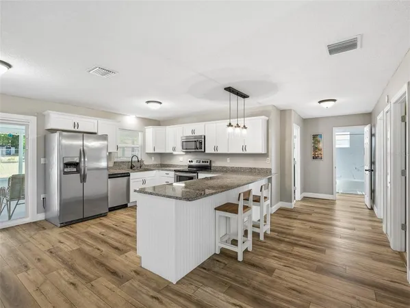 a large kitchen with stainless steel appliances granite countertop a stove and a refrigerator