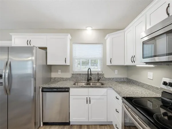 a kitchen with stainless steel appliances granite countertop a sink refrigerator and cabinets