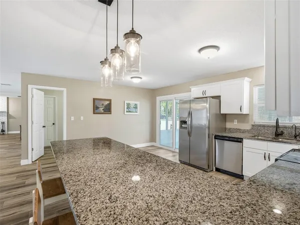 a kitchen with stainless steel appliances granite countertop a refrigerator a stove top oven a sink and dishwasher with wooden floor