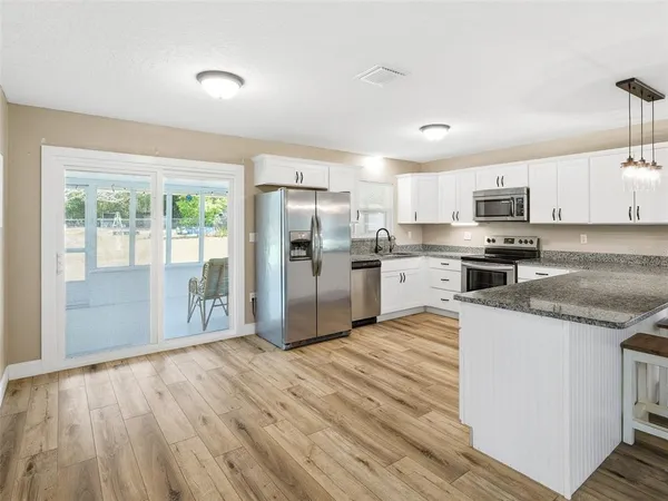 a room with a stove a sink wooden floor and window