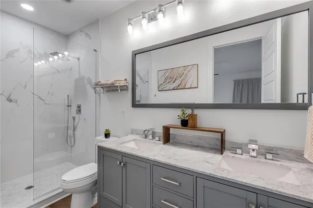 a bathroom with a granite countertop sink a toilet and shower