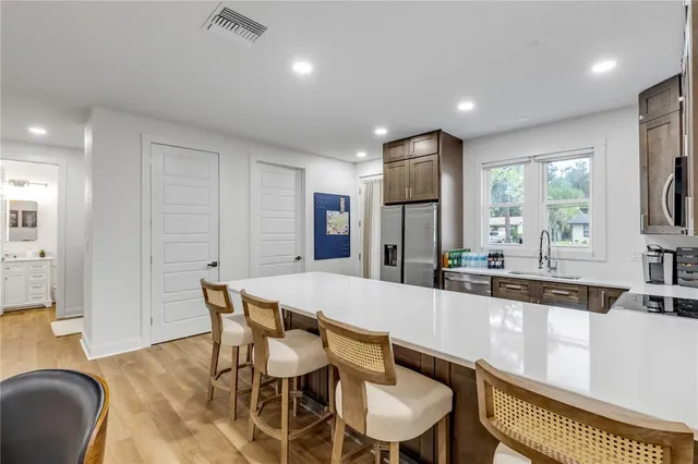 a large white kitchen with a stove a sink dishwasher and a refrigerator with wooden floor