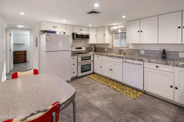 a kitchen with granite countertop a sink stainless steel appliances and white cabinets