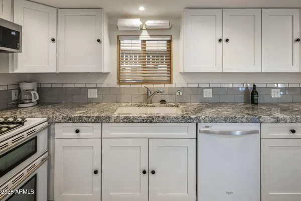 a kitchen with granite countertop white cabinets and white appliances