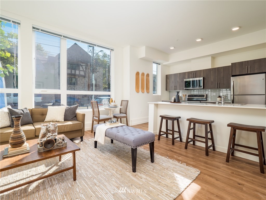 a living room with stainless steel appliances kitchen island furniture and a large window