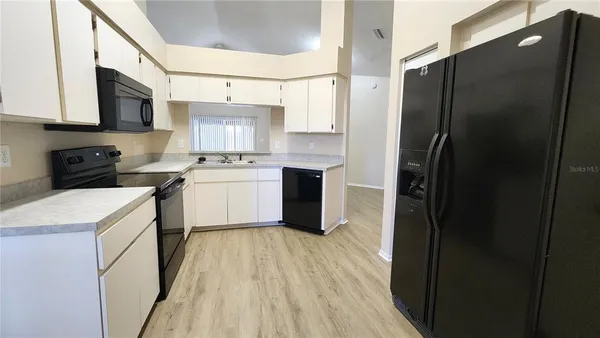 a kitchen with stainless steel appliances a refrigerator a sink a stove and white cabinets