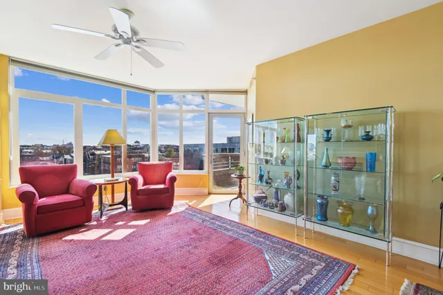 a living room with furniture a ceiling fan and a floor to ceiling window