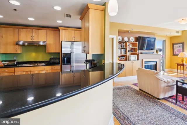 a kitchen with stainless steel appliances granite countertop a refrigerator a stove and a sink with wooden floor