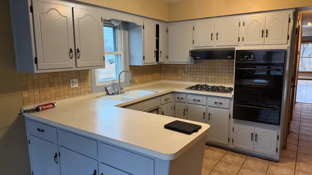 a kitchen with granite countertop a sink a stove and cabinets