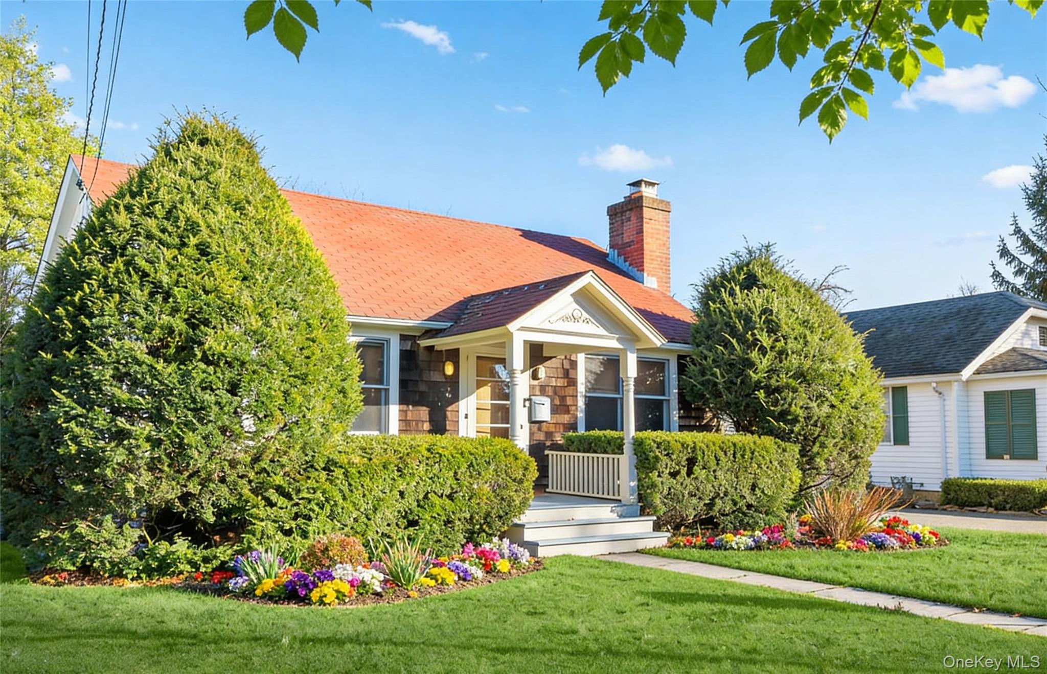 a front view of a house with a yard and potted plants