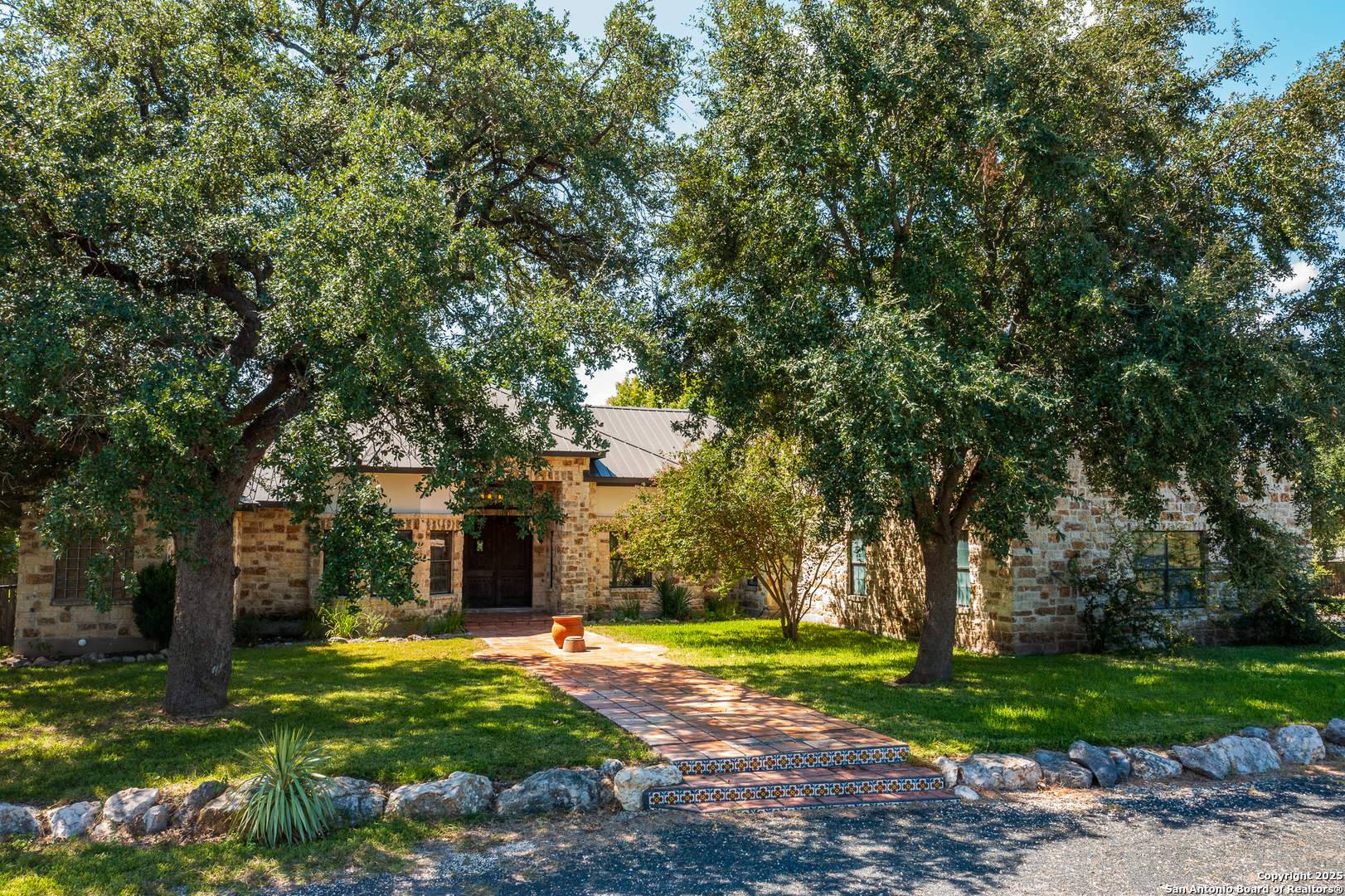 a front view of a house with garden and trees