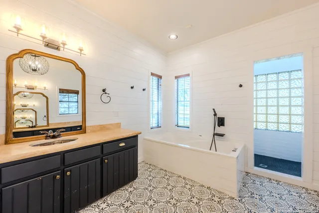 a spacious bathroom with a tub sink and mirror