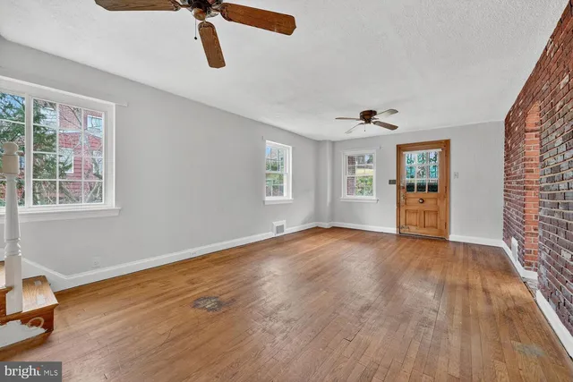 a view of an empty room with window and wooden floor