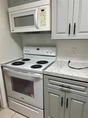 a kitchen with granite countertop white cabinets and white appliances