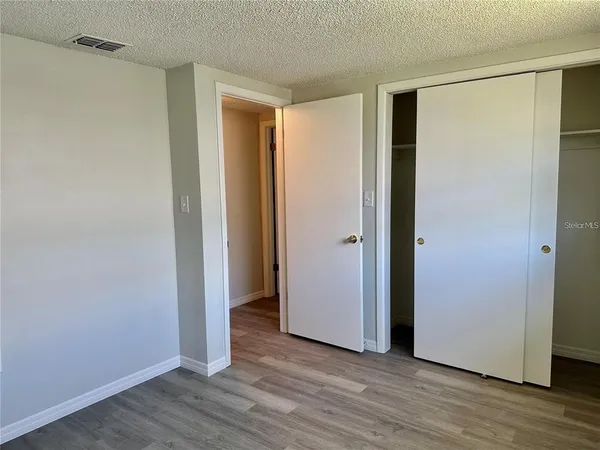a view of an empty room with wooden floor and closet