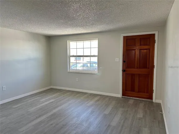a view of an empty room with wooden floor and closet