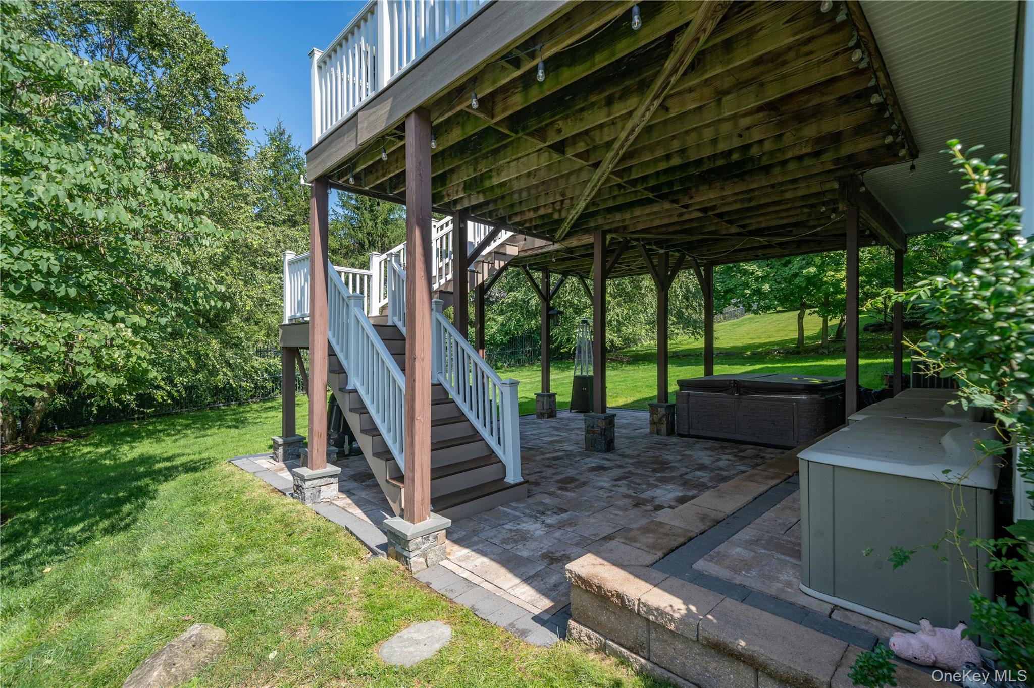 53 Tarryhill Road Tarrytown, NY 10591 - Photo 29 of 35 Just outside the recreation room, the patio offers a relaxing outdoor retreat with a hot tub and easy access to the backyard, while a staircase connects directly to the expansive deck above.