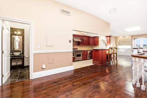 a living room with stainless steel appliances kitchen island granite countertop a refrigerator and cabinets
