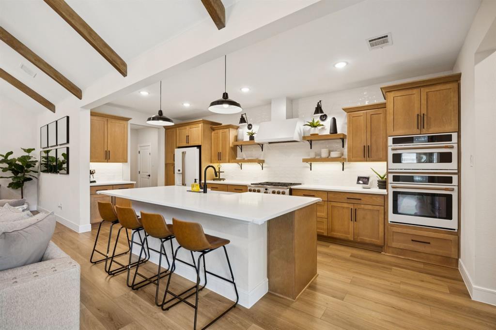 1415 Potenza Road Fate, TX 75087 - Photo 21 of 29 a kitchen with stainless steel appliances kitchen island granite countertop a stove a sink dishwasher and a refrigerator with wooden floor