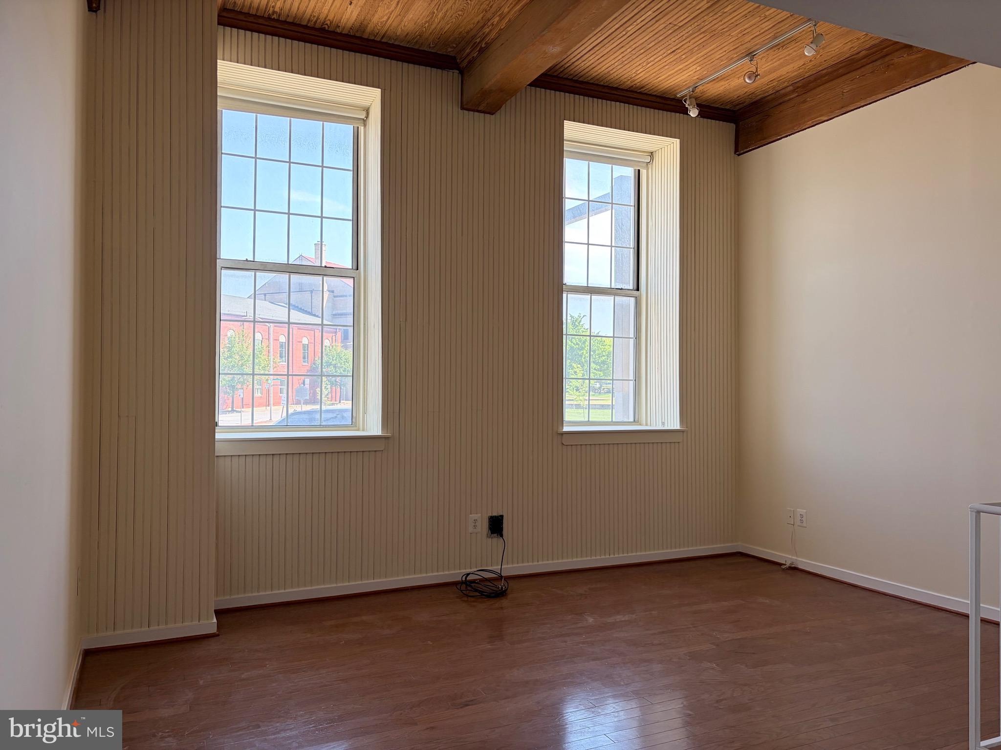 2639 Boston Street, Unit 102 Baltimore, MD 21224 - Photo 2 of 6 an empty room with wooden floor and windows