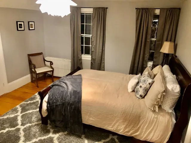 a bed sitting in a bedroom next to a window and chair