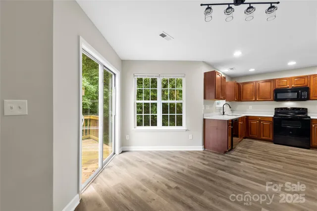a large kitchen with stainless steel appliances granite countertop a refrigerator a sink dishwasher a stove and a dining table with wooden cabinet