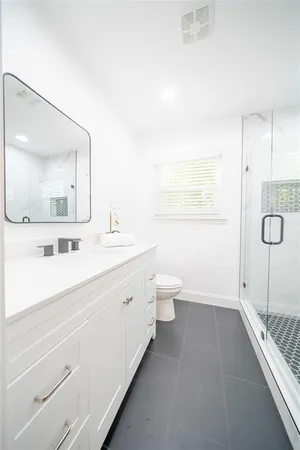 a bathroom with a double vanity sink toilet mirror and shower