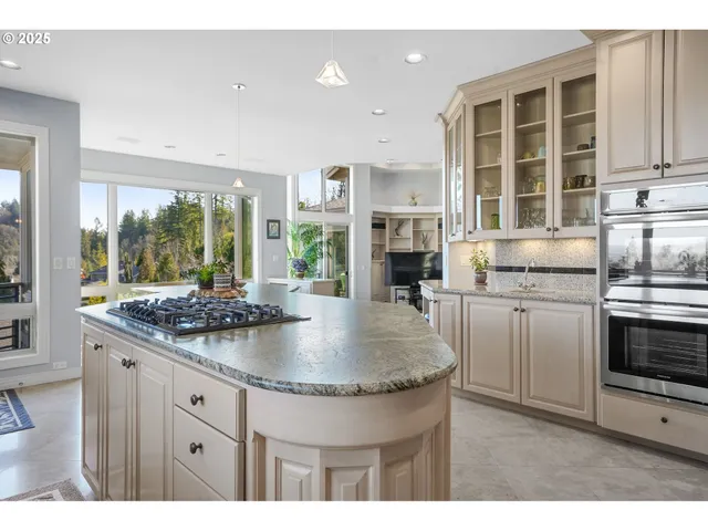a kitchen with kitchen island granite countertop a stove a sink and a granite counter tops with white cabinets