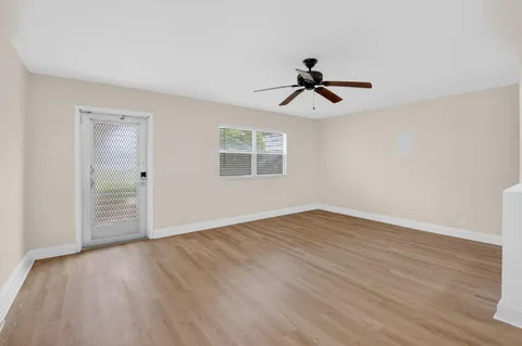 a view of empty room with wooden floor and fan