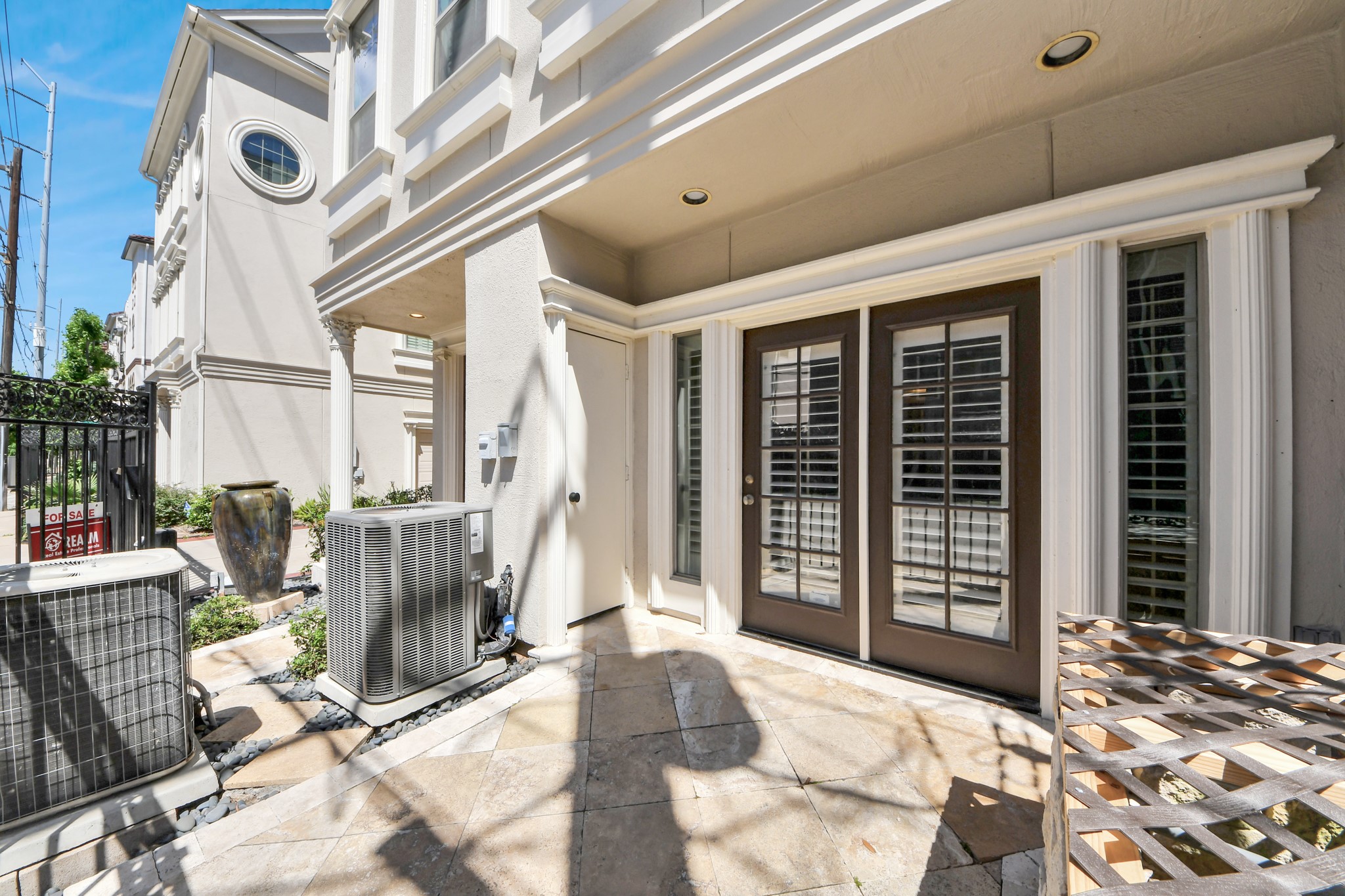 710 Jackson Hill Street Houston, TX 77007 - Photo 29 of 31 Inviting patio area with double doors featuring large glass panels. The space is paved and surrounded by tasteful landscaping, offering a private and serene outdoor setting.