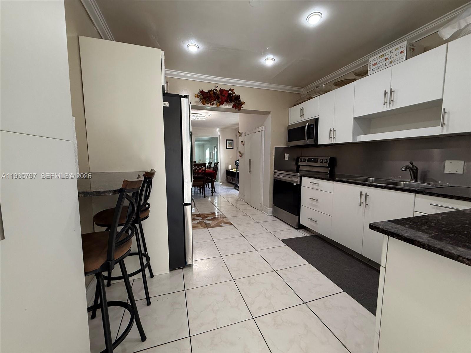 79 Northwest 143rd Street Miami, FL 33168 - Photo 15 of 37 a kitchen with a sink a refrigerator and chairs
