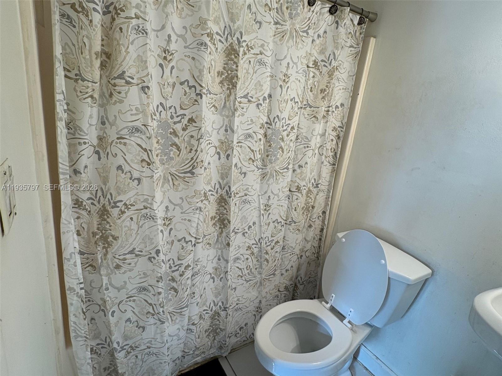 79 Northwest 143rd Street Miami, FL 33168 - Photo 35 of 37 a white toilet sitting next to a shower curtain