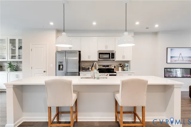 a kitchen with kitchen island a dining table chairs stainless steel appliances and cabinets