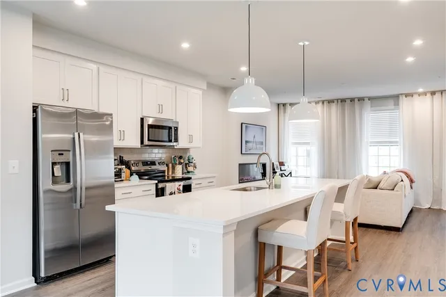 a kitchen with stainless steel appliances kitchen island granite countertop a refrigerator a stove a sink and a center island with wooden floor