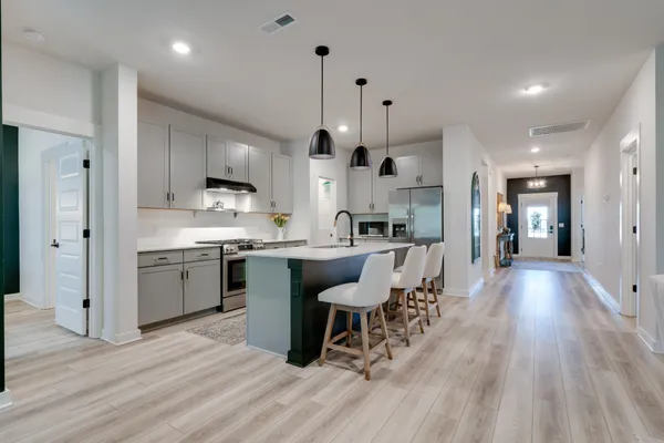 a kitchen with stainless steel appliances a stove a sink a oven a dining table and chairs