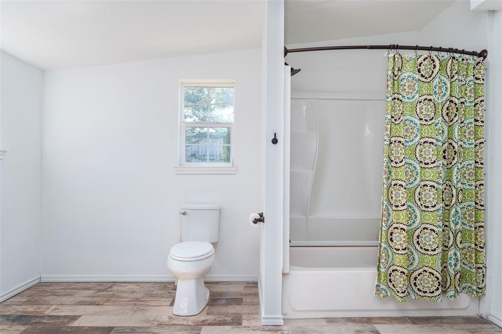 310 North Road Kennedale, TX 76060 - Photo 17 of 23 Windowed bathroom featuring a toilet, a full bathtub, and wood-finish flooring