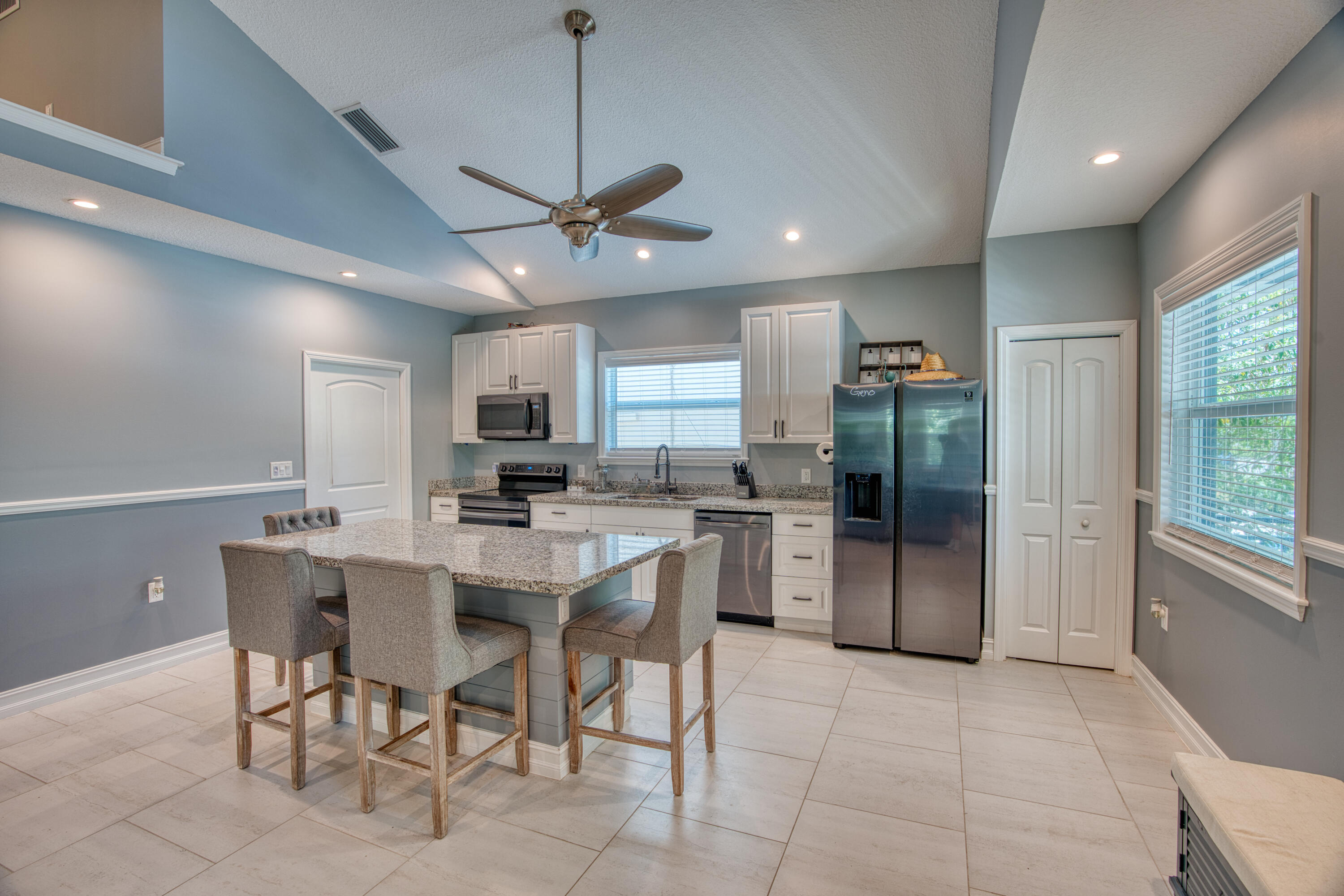 499 Beach Road Tavernier, FL 33070 - Photo 11 of 53 a kitchen with stainless steel appliances granite countertop a refrigerator a sink a stove and a dining table with wooden floor