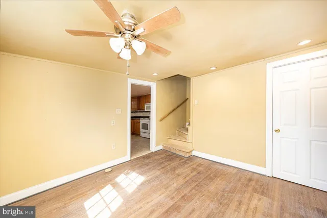 a view of empty room with wooden floor and fan
