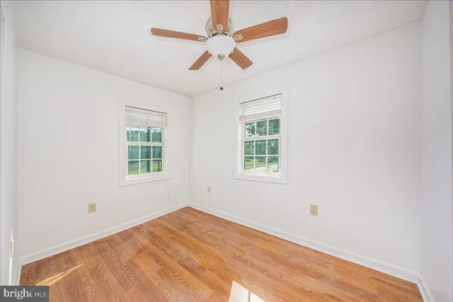 an empty room with a window and a ceiling fan