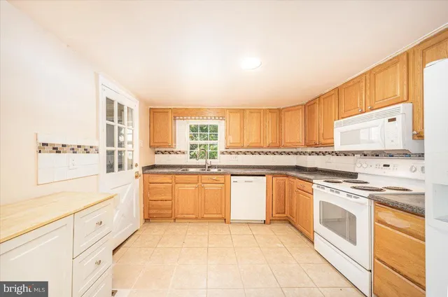 a large kitchen with granite countertop white cabinets and white appliances